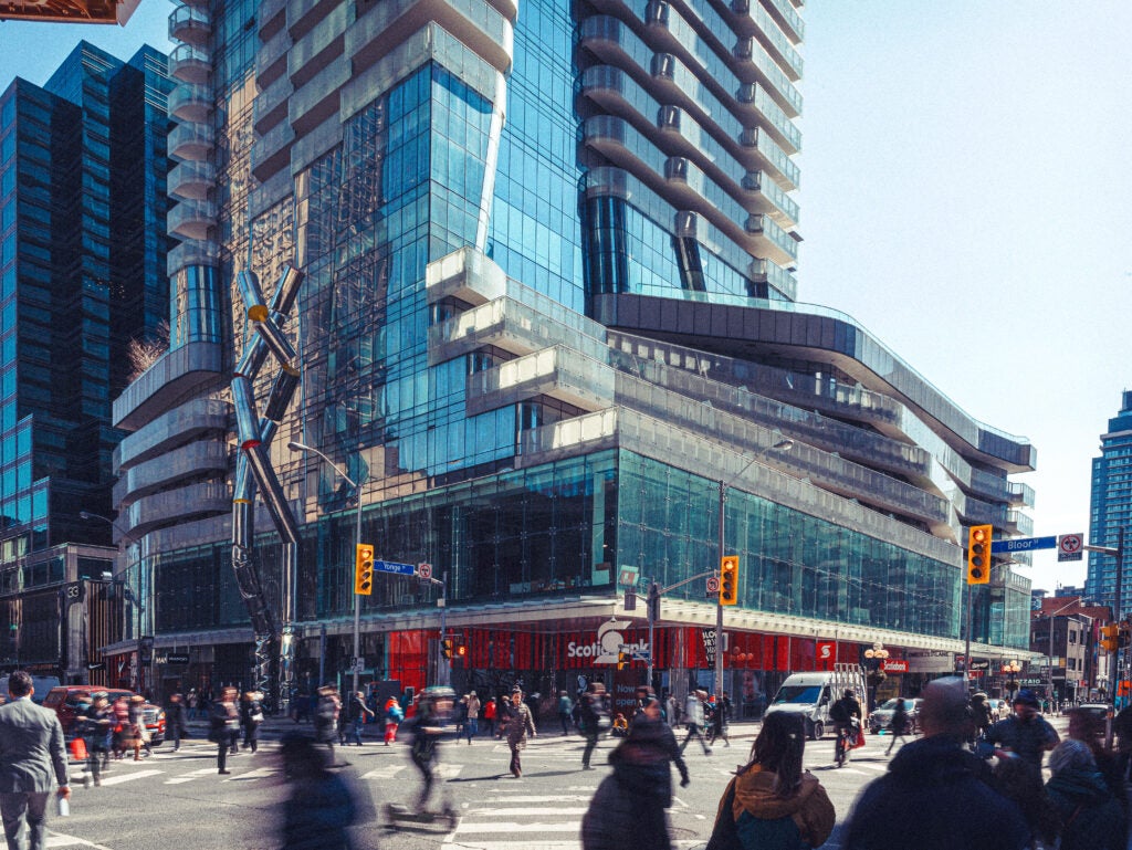 Corner of Yonge and Bloor facing new scotiabank at One Bloor East with people and cars at the intersection
