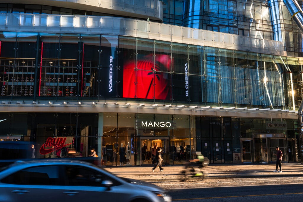 Facade of Mango at One Bloor East with cars, cyclists and people passing by
