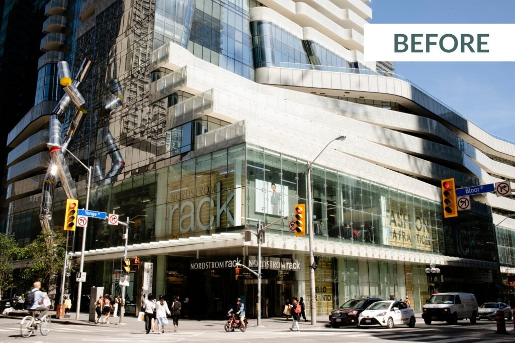 Corner of Yonge and Bloor with facade of building showing Nordstrom rack with people and cars going through intersection